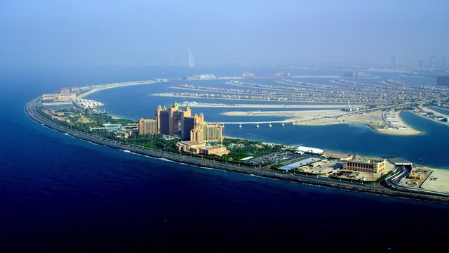 A panoramic view of the Atlantis The Palm, lush green treets, beautiful fronds and the Burj Al Arab on the horizon, Aerial, 6-axis stabilized gimbal, Shotover F1, 8K, parallax.