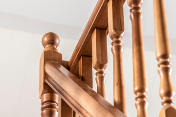 Element of a wooden interior staircase. Wooden baluster close-up.