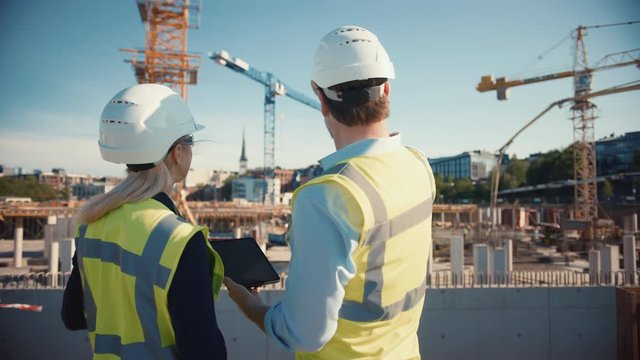 Male Civil Engineer and Young Female Building Architect Use a Tablet Computer on a City Construction Site