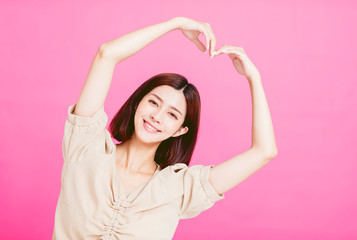 Fototapeta na wymiar smiling young woman with heart shape gesture