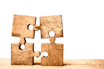 4 Four brown pieces of puzzle stand on wooden table isolated on  white background. empty copy space...