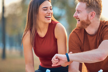 Modern couple making pause in an urban park during jogging / exercise.