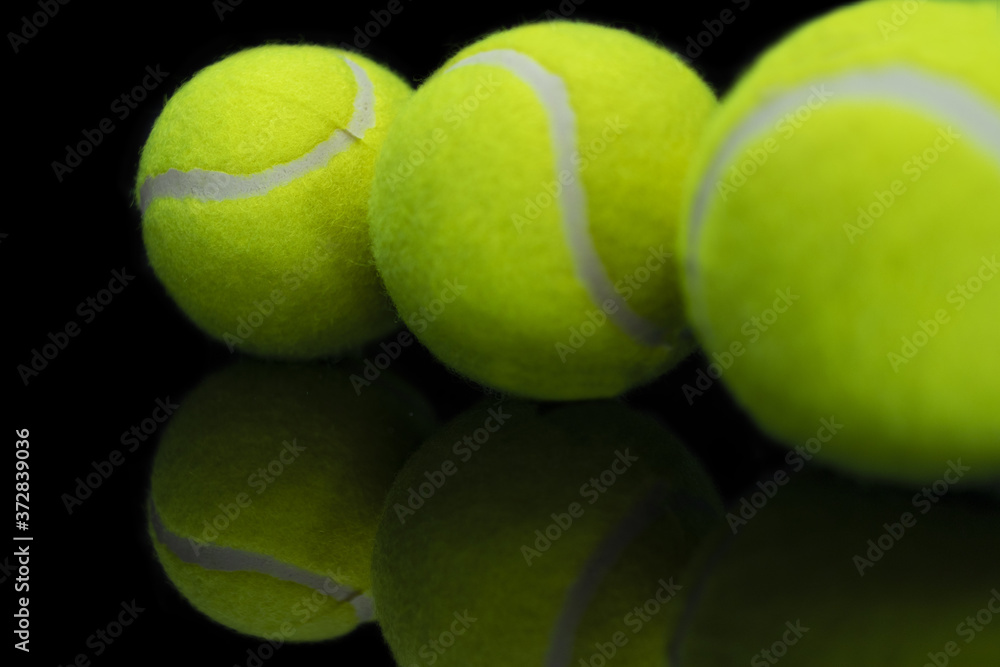 Sticker Closeup shot of the reflection of three tennis ball on a reflective black surface