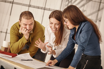 Three architects standing at a desk and discussing a project