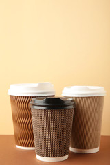 Three brown cups of coffee on beige background. Vertical foto