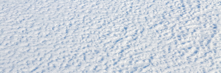 Natural snow texture. The surface of the snow crust. Snowy ground. Winter background with snow patterns. Perfect for Christmas and New Year design. Closeup top view.