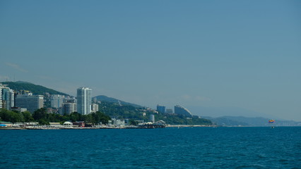 Obraz premium Panorama of the coast of Sochi in summer. Large-format. Black Sea, Russia. View from the sea. No people. Sunny day. Modern city on the beach.