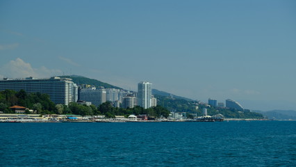 Fototapeta na wymiar Panorama of the coast of Sochi in summer. Large-format. Black Sea, Russia. View from the sea. No people. Sunny day. Modern city on the beach.