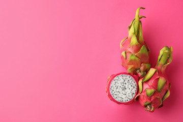 Delicious cut and whole dragon fruits (pitahaya) on pink background, flat lay. Space for text