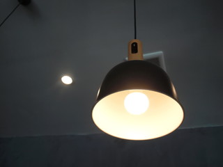 Illuminated lamps hang on the dark ceiling. Use modern style interior decoration. Focus close and choose the subject.
