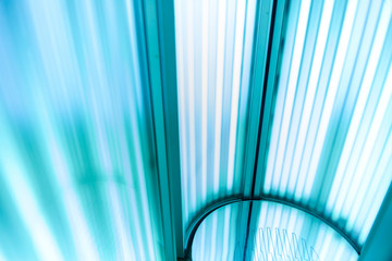 Vertical Tanning turbo Solarium Light Machine with glowing blue light ultraviolet lamps for tanning and skin care. Empty tanning Modern  solarium, inside. Open Solarium door. Horizontal photo shot. 