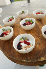 bowls of yogurt and fresh fruit on a wooden board.