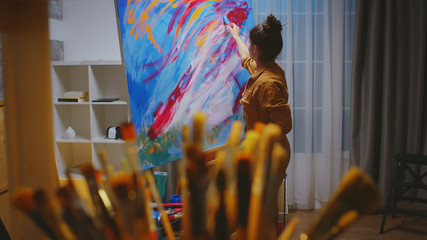 Artist choosing the right paint brush in art studio for her masterpiece.