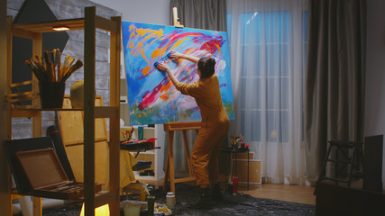 Painter using fingers on large canvas making a masterpiece in art studio.