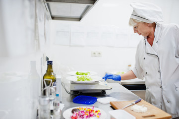 Female chef preparing salad in italian restaurant kitchen.