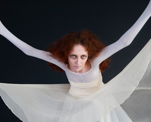 An image for halloween, a red-haired woman in the image of a witch in a white outfit with a pale deathly face