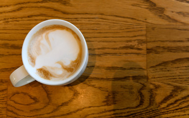 Top view of hot cappuccino coffee cup on wooden table in coffee cafe. copy space for adding text