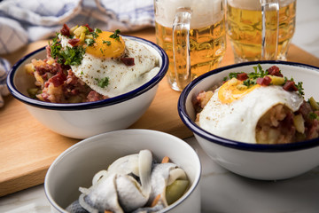 Norddeutscher Hamburger Labskaus mit Rindfleisch Corned Beef, Rote Beete, Kartoffeln, Saure Gurken, Spiegelei, Rollmops und Bier auf Marmor