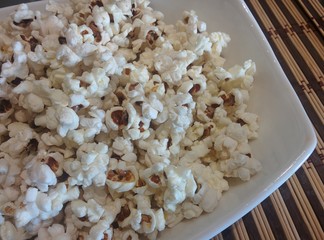 popcorn on white plate close up  food ingredient healthy snack background texture stay home cinema concept