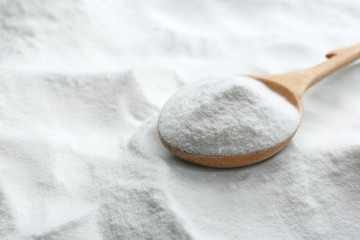 Wooden spoon on baking soda, closeup view