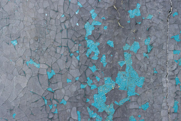 Peeling paint on the wall. Old concrete wall with cracked flaking paint. Weathered rough painted surface with patterns of cracks and peeling. Grunge texture for background and design. High resolution.