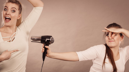 Woman drying friend armpit with hair dryer