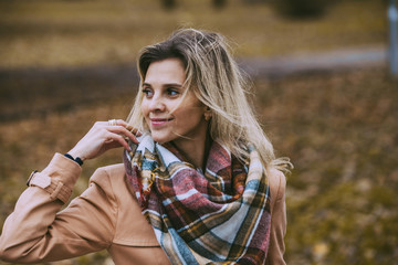 Attractive blonde woman in autumn park in beige coat