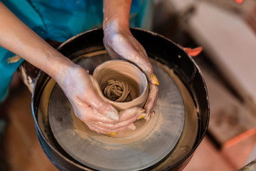 woman potter hands makes on the pottery wheel clay pot, close up. Potter's wheel. Pottery concept. - 372846094