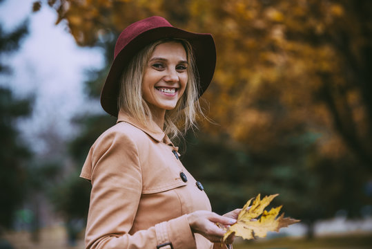 Attractive blonde woman in autumn park in beige coat