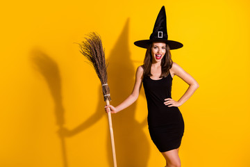 Portrait of her she nice-looking attractive pretty slender cheerful cheery lady wizard holding in hand broom magic season event isolated bright vivid shine vibrant yellow color background
