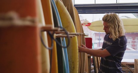 Caucasian male surfboard maker checking one of the surfboards in his studio - Powered by Adobe