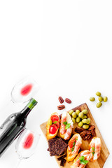 Wine appetizer. Toasts, nuts, olives on white desk top view copy space