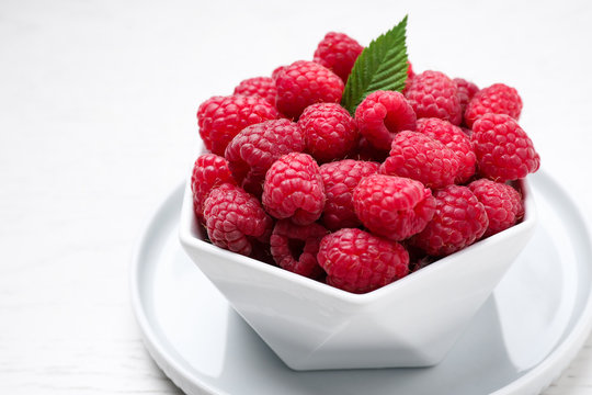 Delicious fresh ripe raspberries in bowl on white table