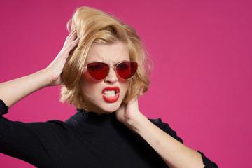 Pretty woman in dark glasses bright makeup black jacket close-up pink background