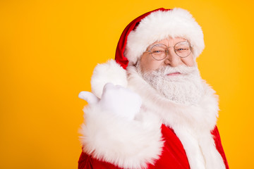 Close up photo jolly holly santa claus point thumb finger copyspace indicate x-mas christmas magic miracle ads wear white gloves cap headwear isolated bright shine color background