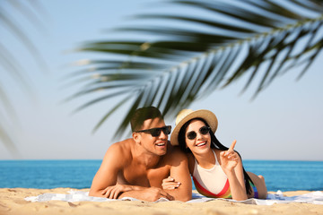 Fototapeta premium Happy couple resting on sunny beach at resort