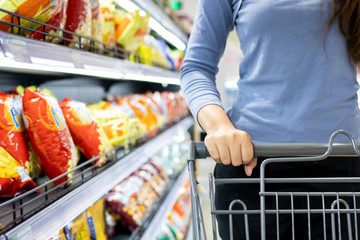 Closeup of a female hand with trolley cart shopping at supermarket. Shopping supermarket concept. © Oulaphone