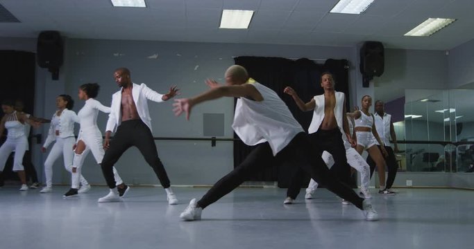 Multi-ethnic group of fit male and female modern dancers practicing dance routine 
