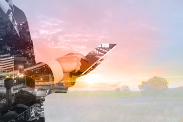 Double Exposure of Businessman and Digital Wireless Tablet with City Building and Skyscraper as concept of Technology business administration.