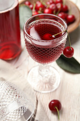 Delicious cherry wine with ripe juicy berries on white wooden table
