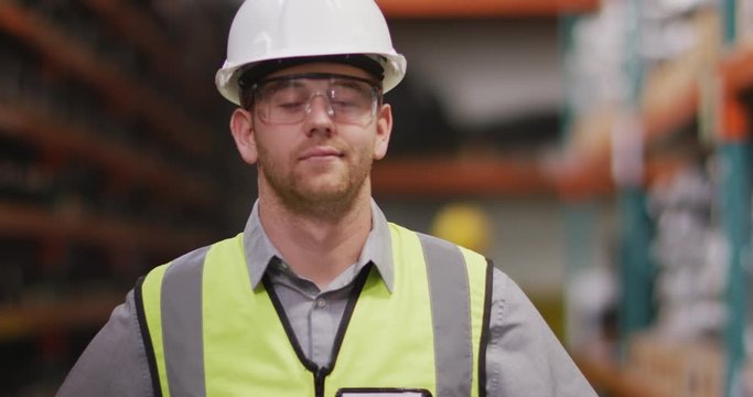 Caucasian male factory worker at a factory looking and smiling to the cameractory workers at a facto