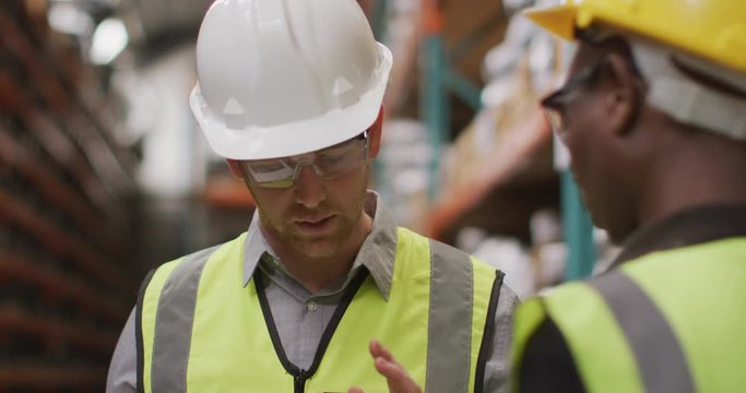 Caucasian male factory worker at a factory wearing vis vests, hard hats and glasses