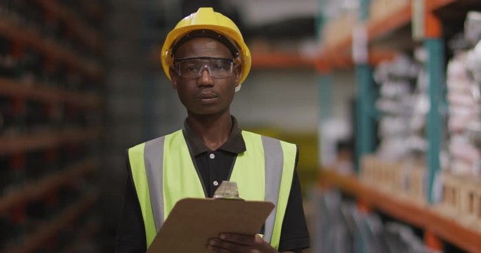 African American male factory worker at a factory looking and smiling to the camera