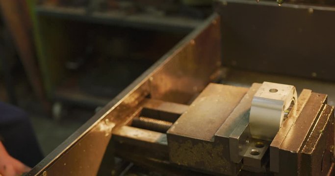 Caucasian male hands factory worker at a factory standing at a workbench and using a hummer