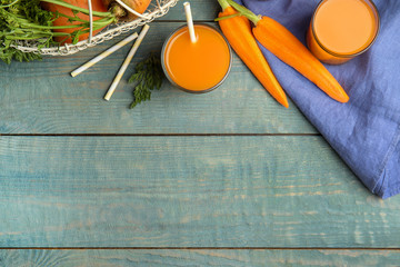 Freshly made carrot juice on wooden table, flat lay. Space for text