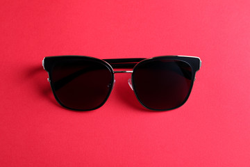 Stylish sunglasses on pink background, top view