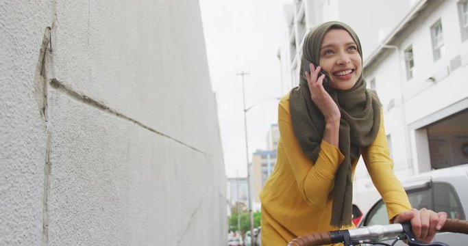 Woman wearing hijab having a phonecall on a bike