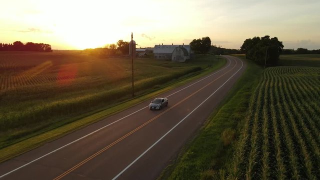 car driving thru fields, farms on the country side in Minnesota during sunset aerial view cinematic
