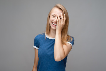 Positive attractive blonde young female, dressed in blue t shirt, being happy to receive good news