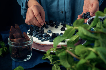 Female hands put blackberry on cottage cheese casserole. Woman decorate cottage cheese pie with berries. Cooking process.